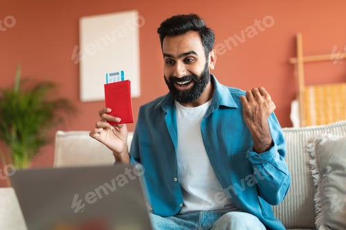 Excited Man Holding Passport with Ticket At Home