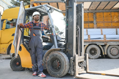Preview: Portrait of a happy African American male worker driving forklift at workplace