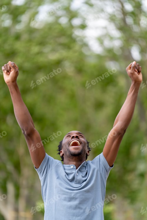 Preview: Excited man screaming with arms outstretched in the park