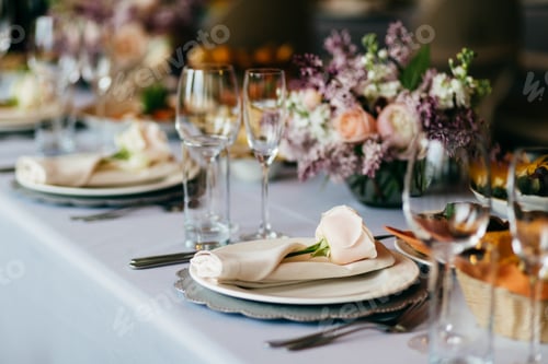 Preview: Table served for special occasion. Empty plate, glasses, forks, napkin and flowers on table
