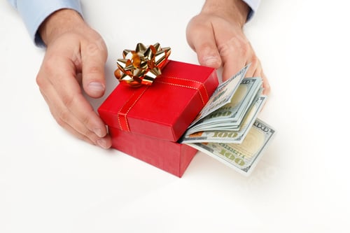 Preview: Man holding gift box with dollar banknotes on white background, closeup