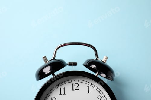 Preview: Black alarm clock on light blue background, top view. Space for text