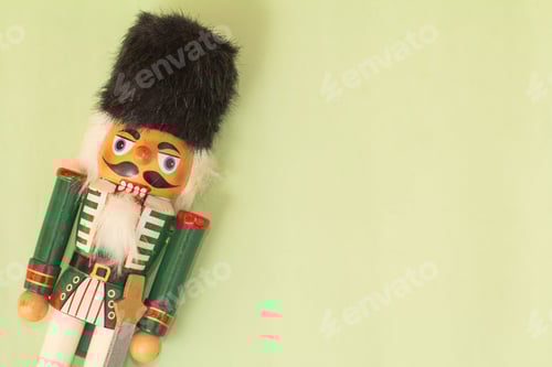 Preview: Interesting beautiful christmas nutcracker soldier on green colored paper surface texture with copy