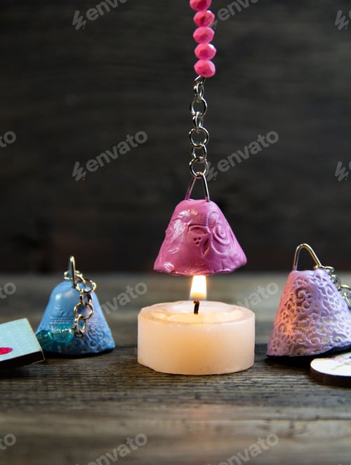 Preview: Closeup of a bell extinguishes a handmade candle on dark background