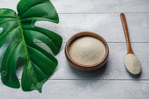 Preview: Collagen powder in bowl and spoon on wooden white background.