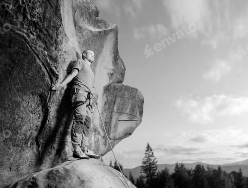 Preview: Male climber climbing big boulder in nature with rope