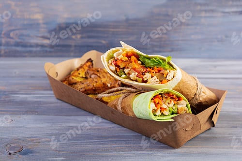 Preview: Delicious shawarma sandwich with chicken and potato on wooden background