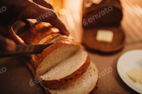 Preview: African American or black man cutting a slice of freshly baked artisan bread