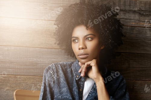 Preview: Close up portrait of attractive good-looking young Africa female with curly haircut resting chin on