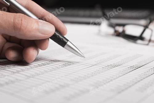 Preview: Close-up of an office worker's hand holding a pen, bills documents and eyeglasses, selective focus.