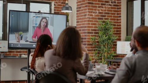 Preview: Diverse team of colleagues using video conference call to chat with woman