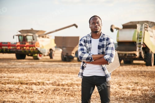 Preview: Standing with arms crossed. Beautiful African American man is in the agricultural field