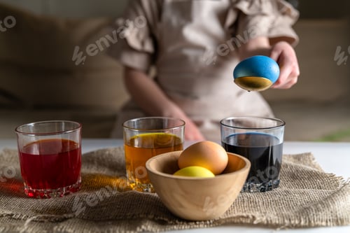 Preview: a girl at home in the kitchen dyes eggs for Easter