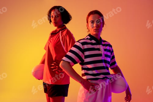 Preview: Portrait of diverse female rugby players with rugby balls over neon pink lighting