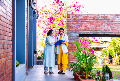 Preview: Young Indian doctor explaining a case report to an elderly patient while walking in a hospital porch