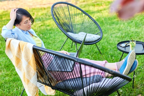 Preview: Freelance woman works on laptop at home in the backyard