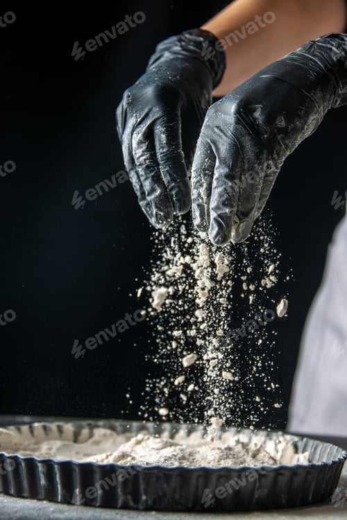 Preview: front view female cook pouring white flour into the pan with her palms on a dark background egg cake