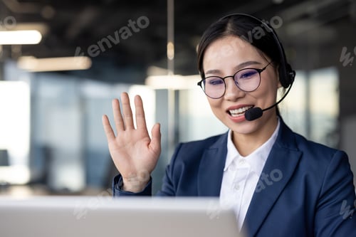 Preview: Asian businesswoman working in an office wearing headset holding a video conference call