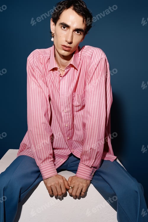 Preview: Handsome man in stylish outfit posing against a vibrant blue background in an artistic setting