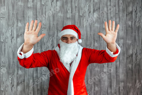Preview: Young Caucasian man dressed as Santa Claus with his hands upwards