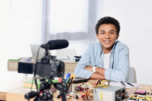 Preview: smiling african american teenager shooting video blog at home
