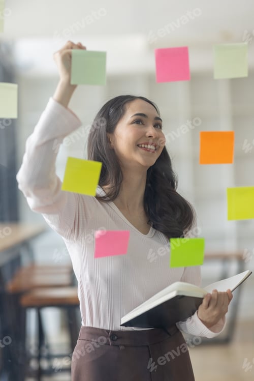 Preview: Business female employee with many conflicting priorities arranging sticky notes commenting and brai