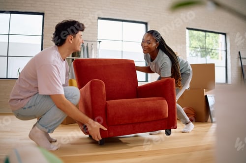 Preview: Happy multiracial couple carrying furniture into their new house.