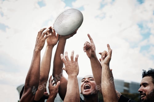 Preview: Cropped shot of a team of rugby players celebrating while standing on the field during the day