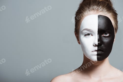 Preview: young beautiful girl with creative white and black bodyart on face looking at camera, isolated on