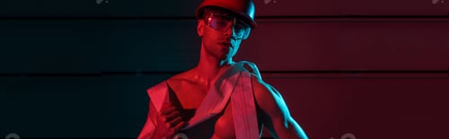 Preview: panoramic shot of sexy fireman in protective equipment holding fire hose in darkness