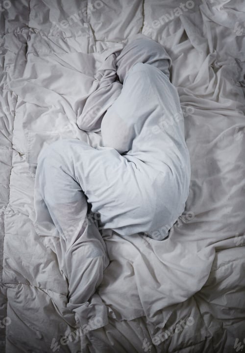 Preview: Shot of a unrecognizable man laying under the covers in a mental asylum
