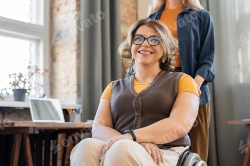 Preview: Happy young smiling woman in wheelchair looking forwards against her friend