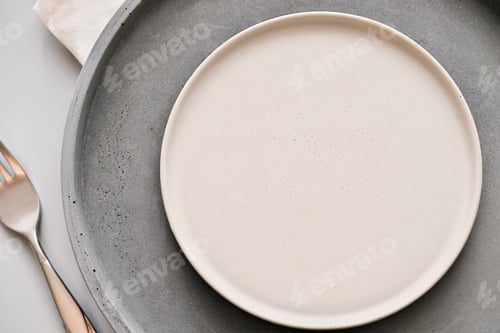 Preview: empty grey plates on a table with fork and knife. spring menu concept. trendy nordic minimal style
