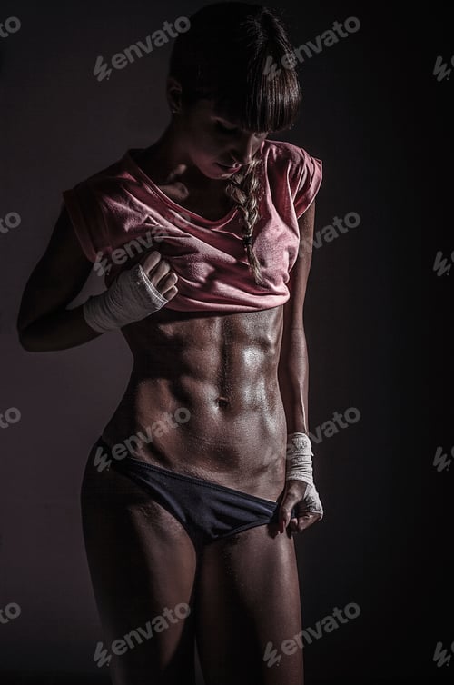 Preview: Portrait of young woman looking down at her abdominal muscles