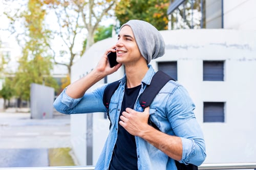 Preview: Outdoor portrait of modern young man with mobile phone in the street.