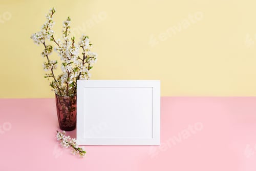 Preview: A bouquet of flowering plum branches in a vase and a photo frame with space for text.