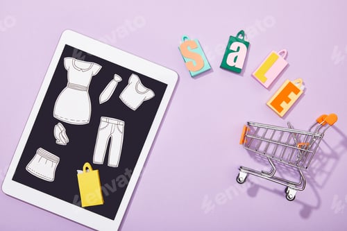 Preview: top view of paper cut of clothes on digital tablet near shopping bags with sale lettering falling