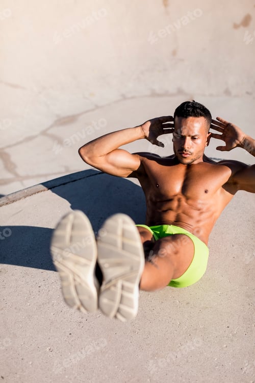 Preview: Barechested muscular man doing sit-ups in a skatepark