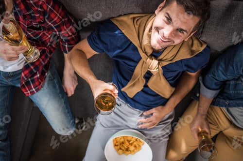 Preview: overhead view of smiling man holding glass of beer with friends near by