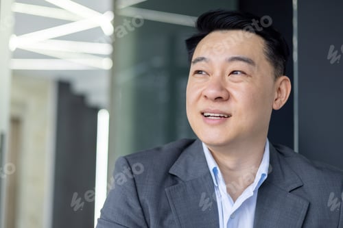 Preview: Smiling Asian businessman in a modern office setting
