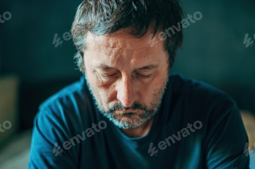 Preview: Unhappy contemplative mature adult man thinking in dark room, depressed sulking male pondering