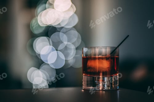 Preview: whiskey bourbon rye old fashion drink on a table in a dark room with holiday bokeh christmas lights
