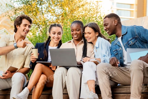 Preview: Diverse students friends sitting on bench outdoors in university campus
