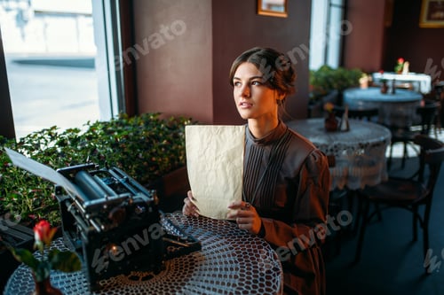 Preview: Happy young woman sits by the table in cafe
