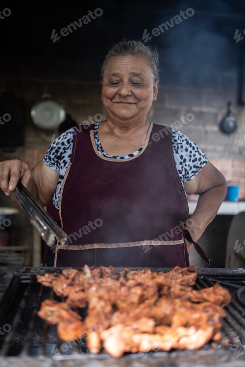 Preview: Latin adult woman cooking meat on a grill