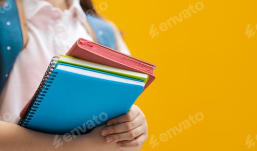Preview: Child with books on background of yellow wall.