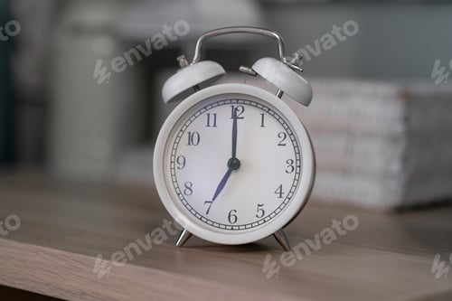 Preview: Close-up of a round white alarm clock on a table in the bedroom.
