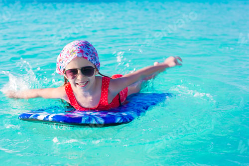 Preview: Little cute girl swimming on a surfboard in the turquoise sea