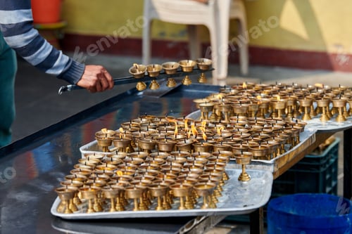 Preview: Nepali temple staff pour out candle oil after wick burns out for replacement
