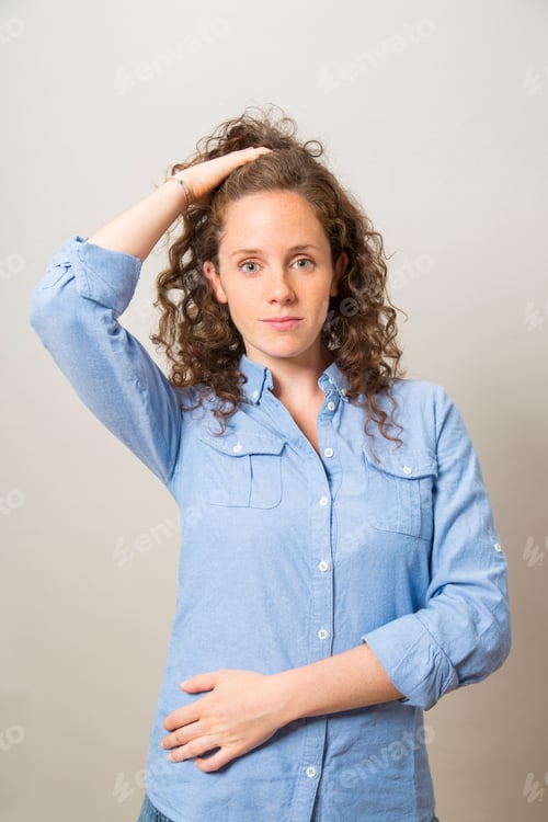Preview: portrait pretty redhead smiling girl with hand in hair looking at camera with on gray background